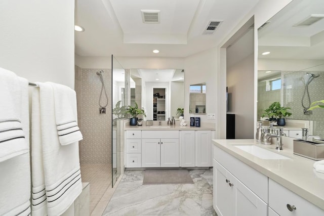 bathroom featuring a tile shower, vanity, and a tray ceiling