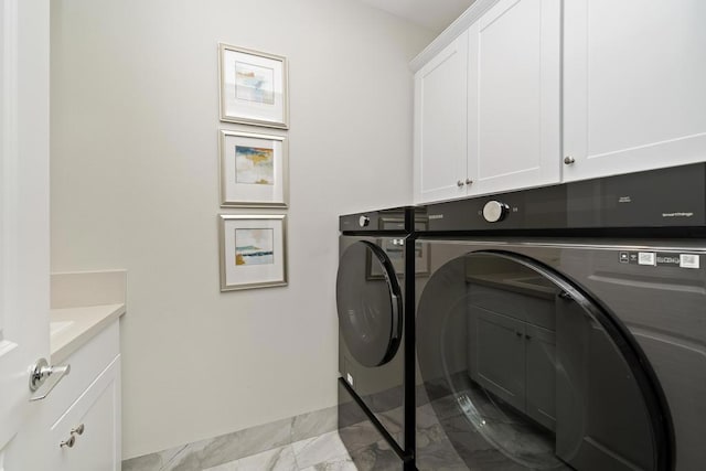 clothes washing area featuring washer and dryer and cabinets