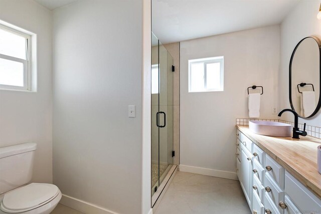 bathroom featuring vanity, toilet, walk in shower, and a healthy amount of sunlight