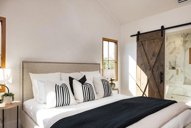 bedroom featuring a barn door, lofted ceiling, and ensuite bath