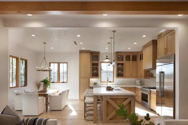 kitchen featuring decorative backsplash, high end appliances, light hardwood / wood-style flooring, an inviting chandelier, and a center island