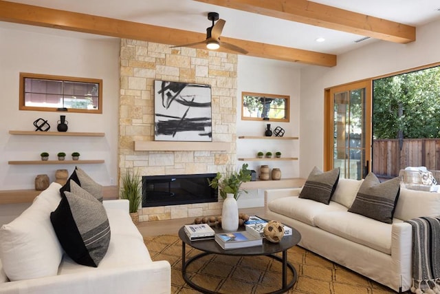 living room with beam ceiling, a fireplace, ceiling fan, and plenty of natural light