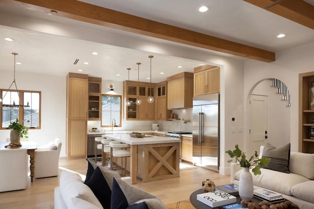 living room with beamed ceiling, light hardwood / wood-style floors, a chandelier, and sink