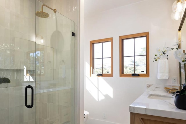 bathroom featuring vanity, toilet, and a shower with door