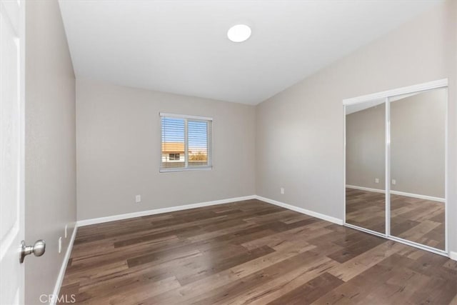 unfurnished bedroom with vaulted ceiling and dark hardwood / wood-style floors