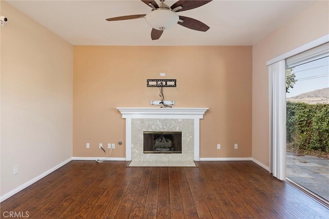 unfurnished living room with a tiled fireplace, ceiling fan, and dark hardwood / wood-style floors