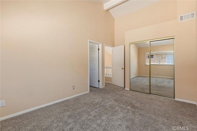 unfurnished bedroom featuring carpet, beamed ceiling, high vaulted ceiling, and a closet