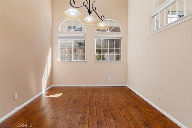 unfurnished dining area with wood-type flooring, a wealth of natural light, and a high ceiling