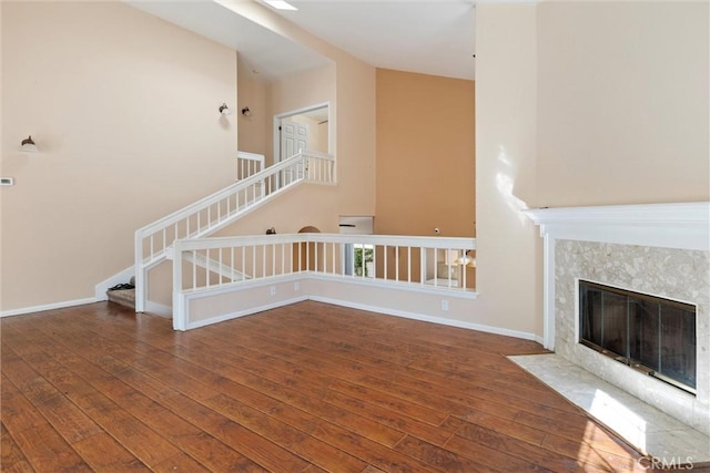 unfurnished living room with a high end fireplace and dark wood-type flooring