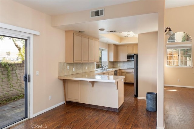 kitchen featuring a kitchen breakfast bar, decorative backsplash, kitchen peninsula, and dark wood-type flooring