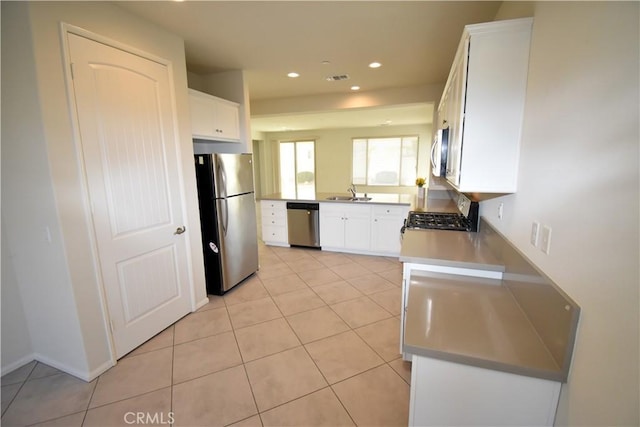 kitchen featuring sink, white cabinets, light tile patterned floors, and appliances with stainless steel finishes