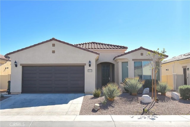 mediterranean / spanish home featuring stucco siding, a garage, driveway, and a tiled roof