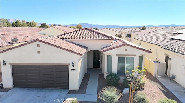 mediterranean / spanish-style house with a garage, stucco siding, driveway, and a tiled roof