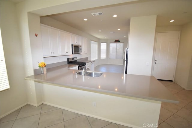 kitchen featuring white cabinetry, sink, stainless steel appliances, kitchen peninsula, and light tile patterned flooring