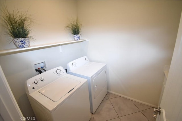 laundry area with independent washer and dryer and light tile patterned floors