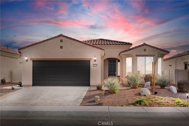 mediterranean / spanish home featuring stucco siding, a garage, driveway, and a tile roof