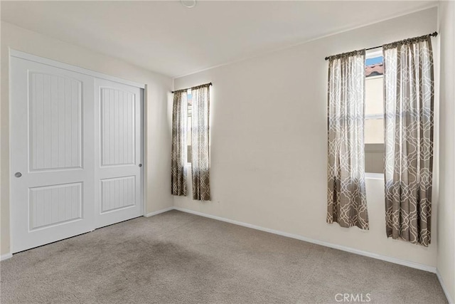 unfurnished bedroom featuring carpet flooring, baseboards, and a closet