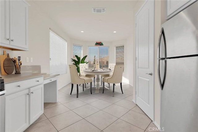 kitchen with light countertops, light tile patterned floors, recessed lighting, freestanding refrigerator, and white cabinets