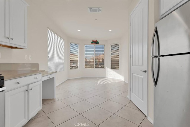 kitchen with white cabinetry, light countertops, light tile patterned floors, and freestanding refrigerator