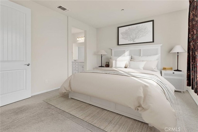 carpeted bedroom featuring visible vents, baseboards, and ensuite bath