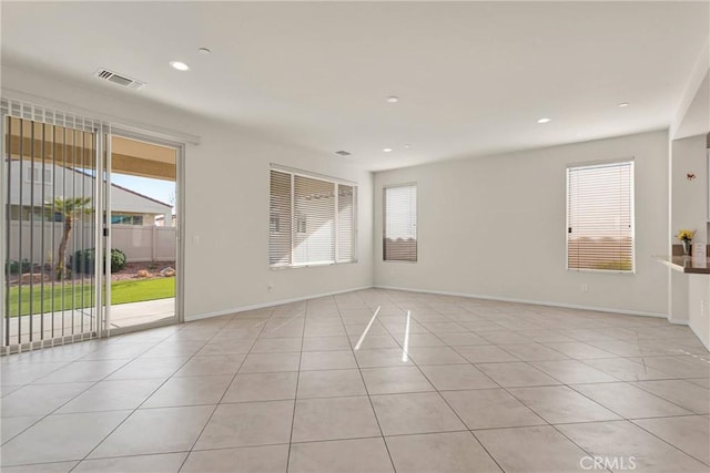 spare room featuring light tile patterned floors, visible vents, and a wealth of natural light