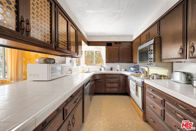 kitchen with tile countertops, appliances with stainless steel finishes, and plenty of natural light