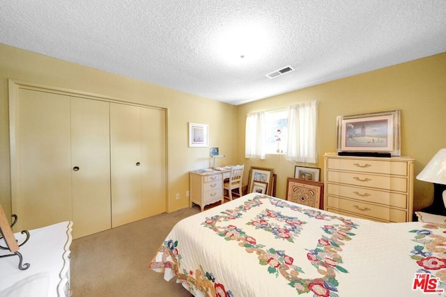 carpeted bedroom with a closet and a textured ceiling