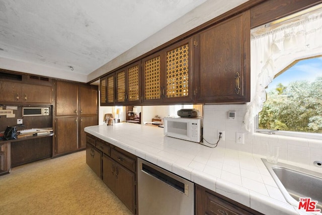 kitchen with sink, dishwasher, tile countertops, dark brown cabinets, and decorative backsplash