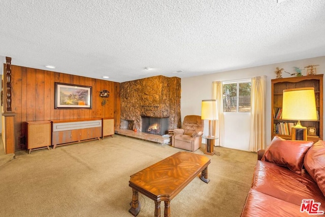 living room featuring light carpet, a stone fireplace, a textured ceiling, and wood walls