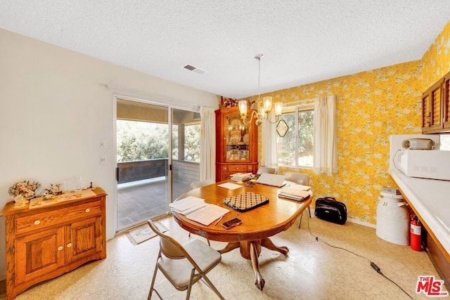 dining space with a textured ceiling and a chandelier