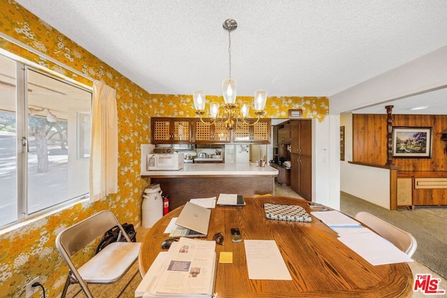 dining room featuring an inviting chandelier, carpet floors, and a textured ceiling