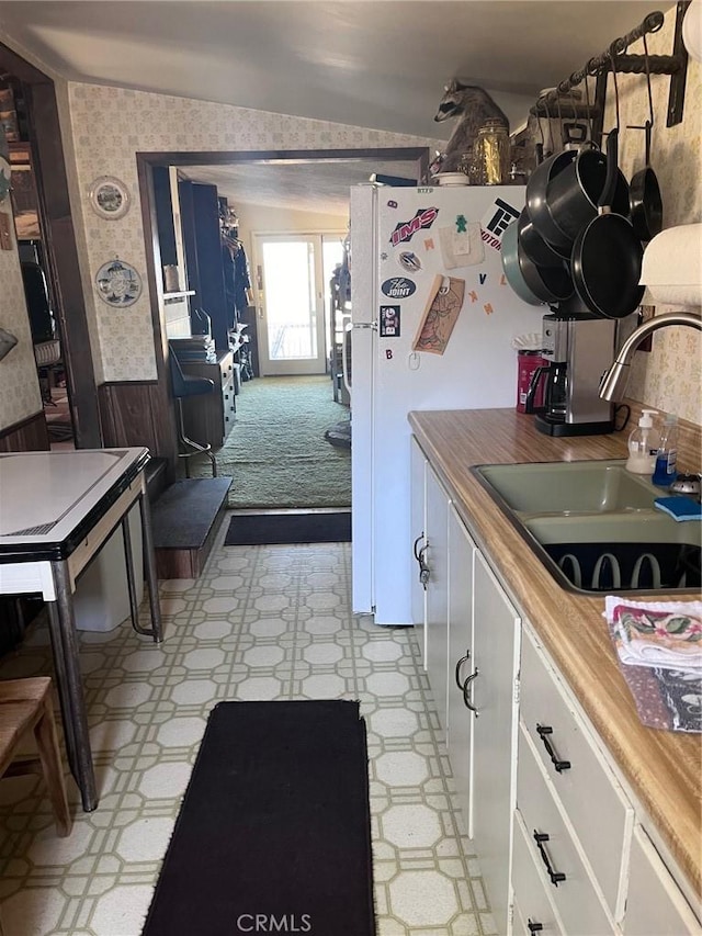 kitchen with wood counters, vaulted ceiling, sink, white refrigerator, and white cabinets