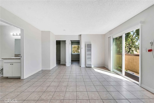 tiled spare room with a textured ceiling and a healthy amount of sunlight