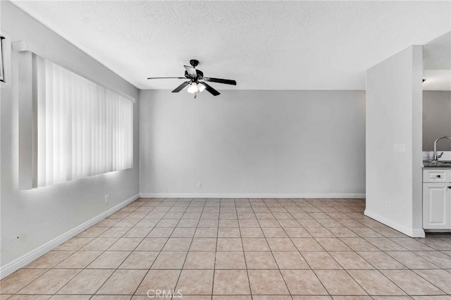 unfurnished room with sink, ceiling fan, a textured ceiling, and light tile patterned flooring