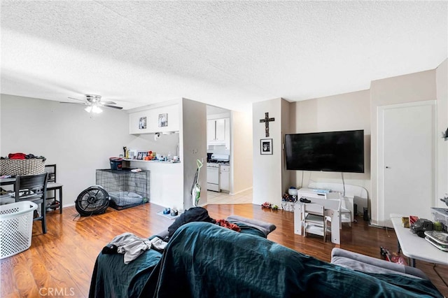 living room with a textured ceiling, light hardwood / wood-style floors, and ceiling fan