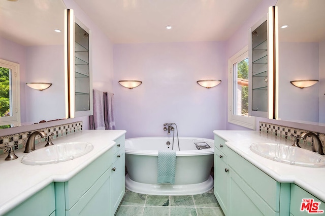 bathroom with vanity, decorative backsplash, a tub, and tile patterned flooring