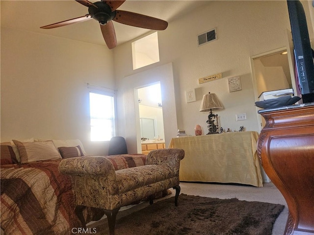 bedroom with connected bathroom, ceiling fan, and a towering ceiling