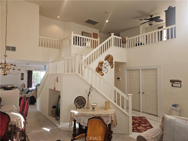 interior space featuring a high ceiling and ceiling fan with notable chandelier