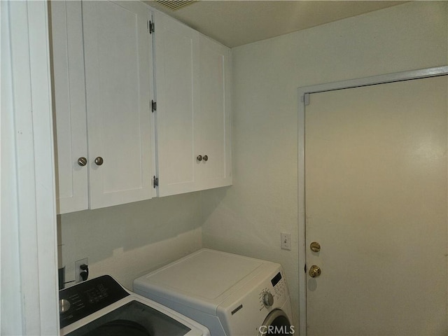 clothes washing area with washer and clothes dryer and cabinets