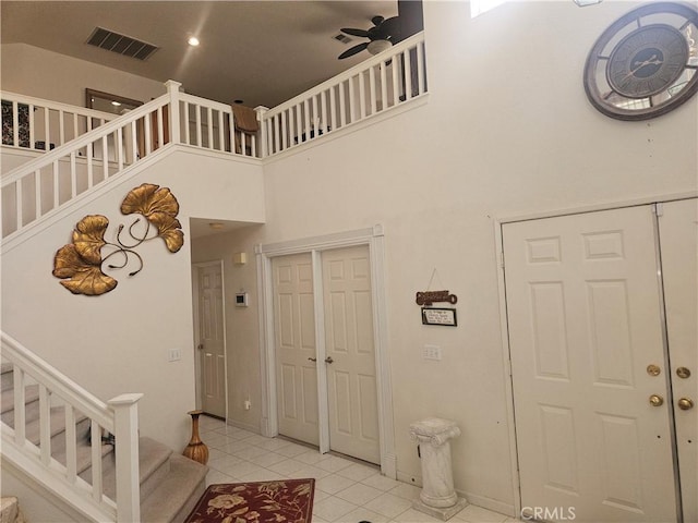 tiled foyer with ceiling fan and a high ceiling