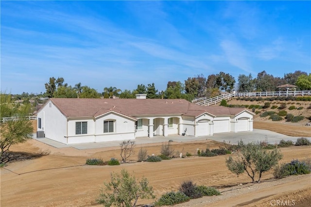 view of front of house with a garage, fence, a tiled roof, driveway, and stucco siding