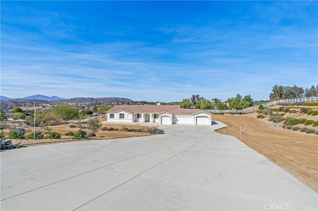 view of front facade featuring driveway, fence, and a mountain view