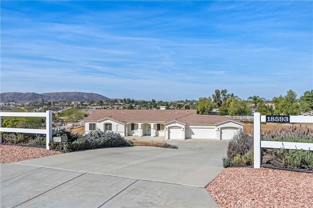 ranch-style home with a mountain view, driveway, an attached garage, and fence