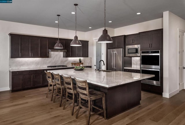 kitchen with a spacious island, stainless steel appliances, dark hardwood / wood-style floors, and hanging light fixtures