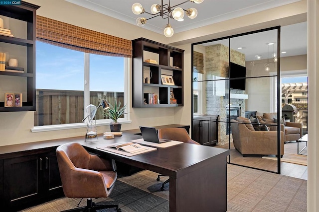 office space with ornamental molding, a chandelier, a stone fireplace, and light hardwood / wood-style floors