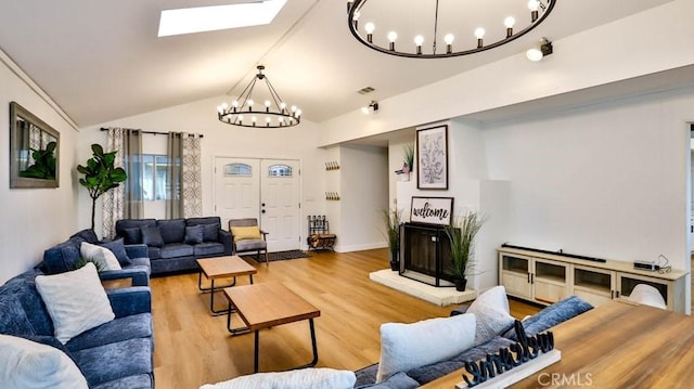 living room with vaulted ceiling with skylight, wood-type flooring, and a chandelier