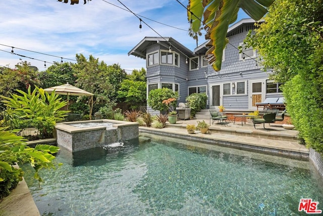 rear view of house featuring pool water feature, a patio, and a pool with hot tub