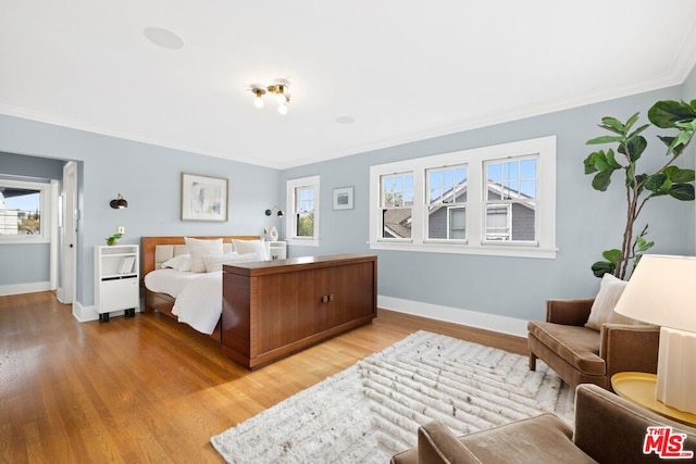 bedroom featuring multiple windows, crown molding, and light wood-type flooring