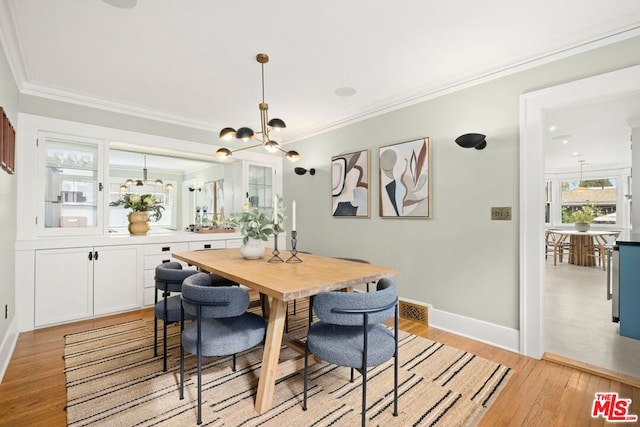 dining area featuring light wood-type flooring and crown molding