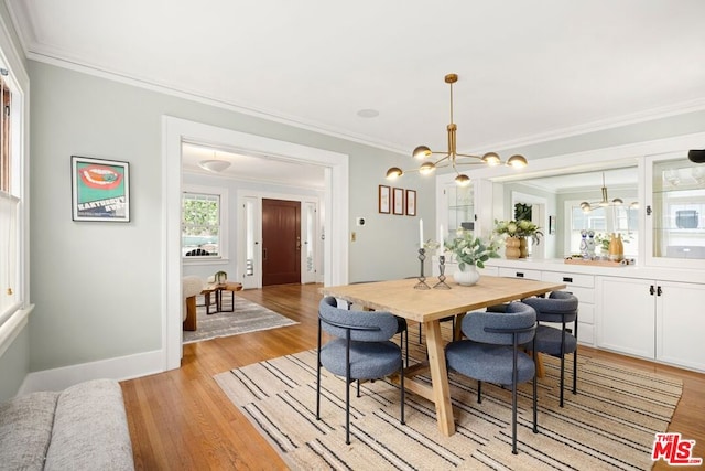 dining space with light hardwood / wood-style flooring, a chandelier, and ornamental molding